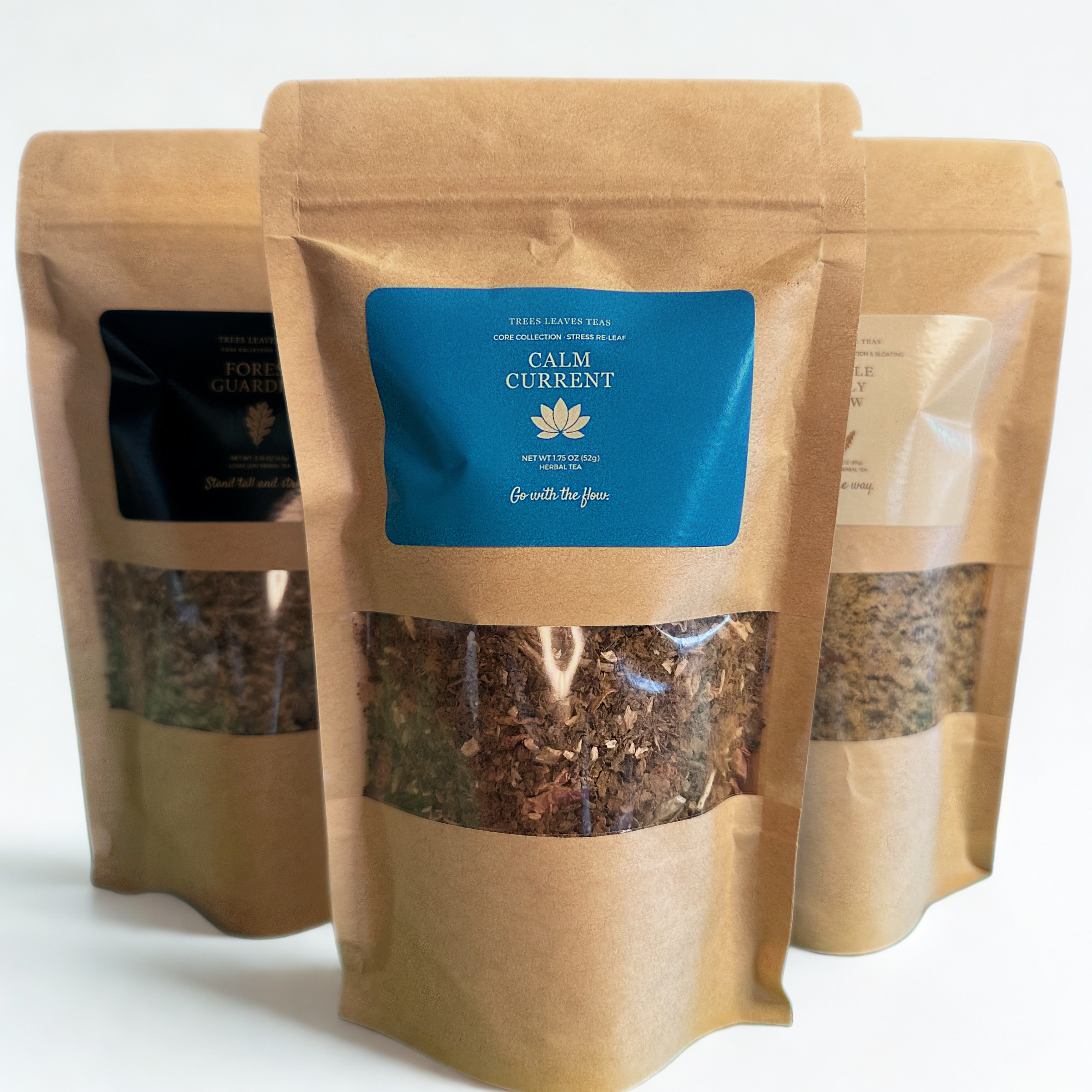 Three brown paper tea bags with visible tea leaves and a blue label by Trees Leaves Teas on a white background