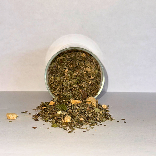 Spilled container of dried herbs on a white surface with a white background